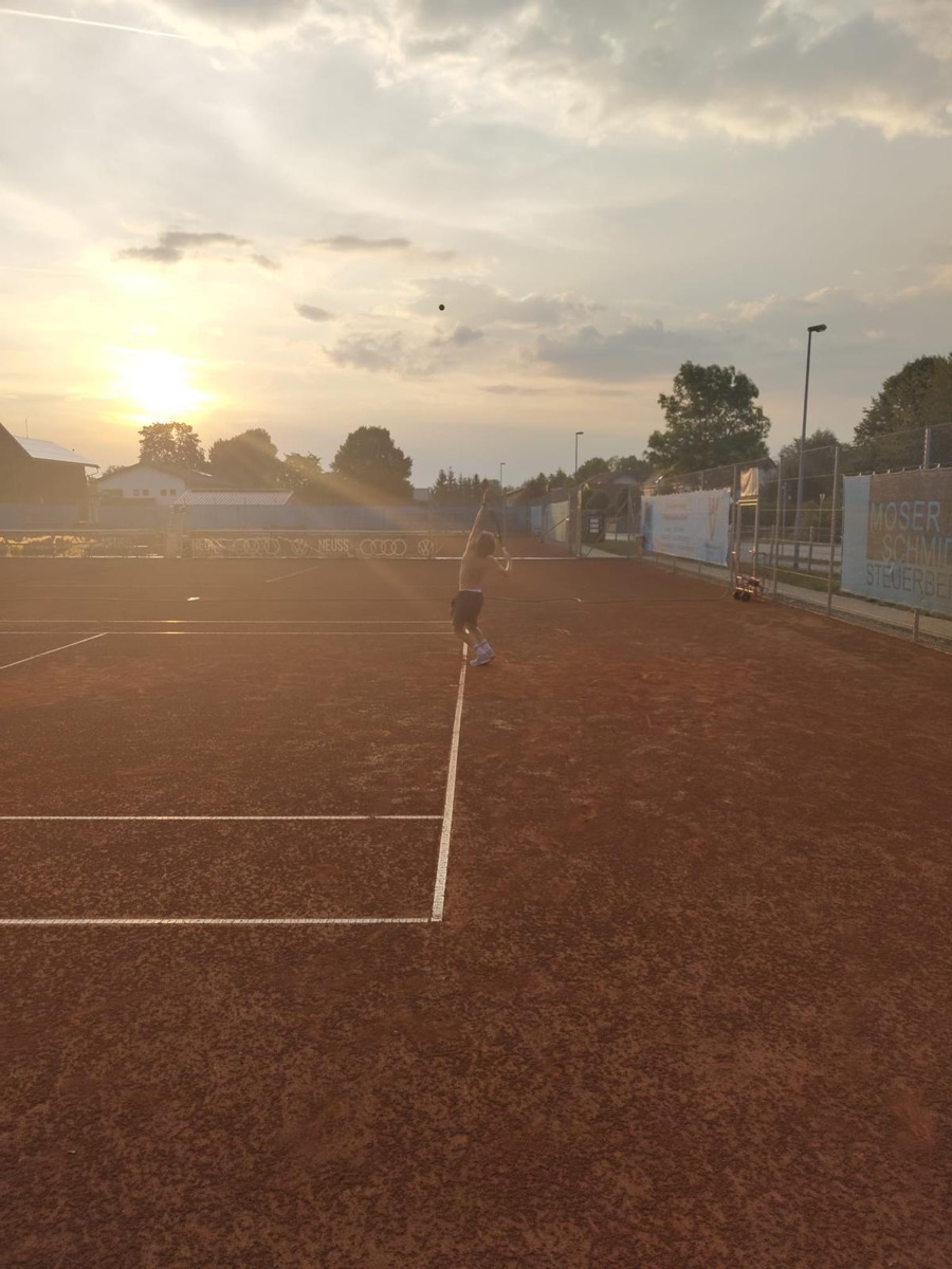 Elias Conrad beim Aufschlag auf einem Sandplatz bei Sonnenuntergang